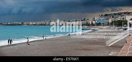 Tourists on beach and dark menacing rain clouds over the city Nice along French Riviera, Côte d'Azur, Alpes-Maritimes, France Stock Photo