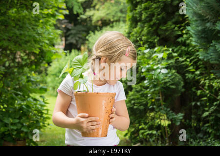 Little girl gardening, holding potted plant in hands Stock Photo