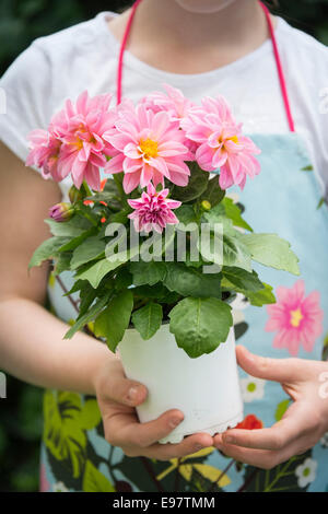 Girl holding pot with flowers in hands Stock Photo