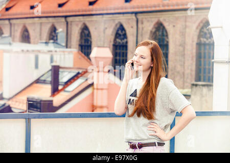 Young woman using smart phone on balcony, Munich, Bavaria, Germany Stock Photo