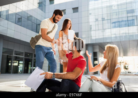 Male students shaking hands on campus grounds Stock Photo