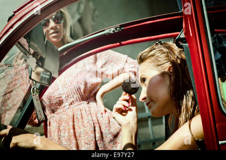 Woman in car applying make-up with brush Stock Photo