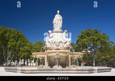vew of fountain in city centre, Nimes, with amphitheatre and arena in background, against a blue sky Stock Photo