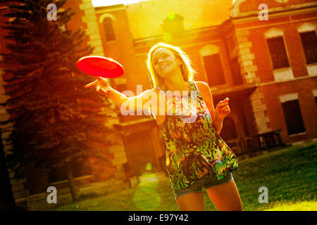 Young woman playing frisbee outdoors with back light Stock Photo