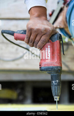 Worker installing wall system materials and insulation over frame of residential home. Los Angeles, California, USA Stock Photo