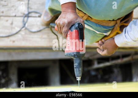 Worker installing wall system materials and insulation over frame of residential home. Los Angeles, California, USA Stock Photo