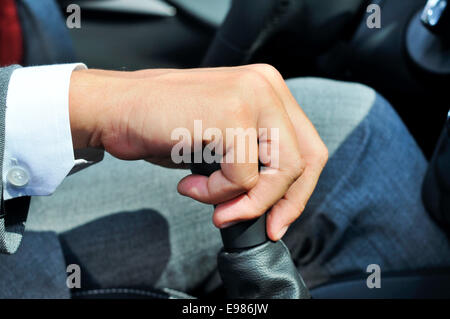 closeup of a man in suit operating the parking brake of a car Stock Photo