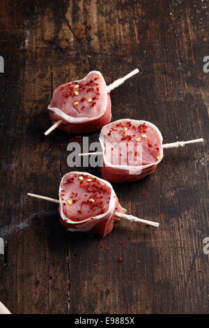 Raw tenderloin steak of pork wrapped in bacon on wooden background with copyspace