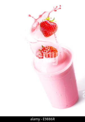 Ripe red fresh strawberries splashing into a glass of blended fruit smoothie with creamy yoghurt Stock Photo