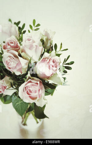 High angle view of a fresh bouquet of delicate pink roses arranged with foliage in a glass vase over a white background with copyspace Stock Photo