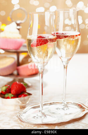 Romantic champagne and strawberries served on a silver tray in elegant flutes with festive party lights Stock Photo