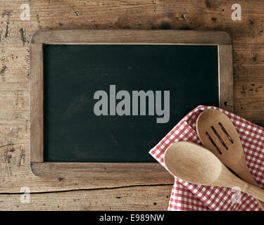 Blackboard on wooden surface and serving spoons Stock Photo
