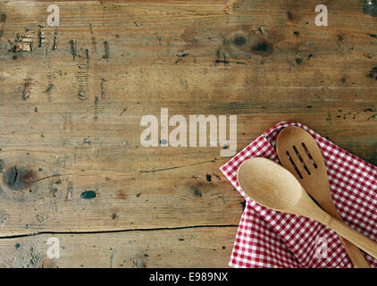 Serving spoons on checkered cloth lying on wooden surface Stock Photo