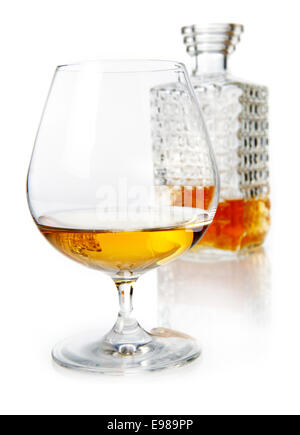 Aged golden brandy or cognac in a snifter with a cut glass decanter on a reflective white studio background Stock Photo
