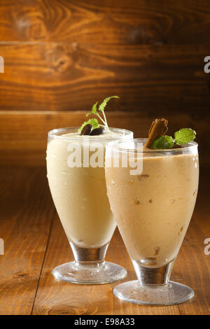 Creamy thick milkshakes or pudding dessert in chilled glasses garnished with chocolate and served on a wooden background with copyspace Stock Photo