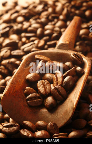 A background of fresh rich, dark coffee beans with a wooden scoop filled with beans Stock Photo