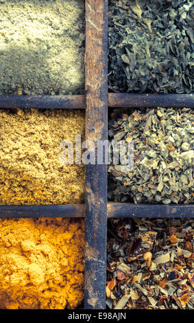 Close up overhead view of assorted dried herbs and spices in an old vintage wooden printers tray for use as seasoning and flavouring in cooking Stock Photo