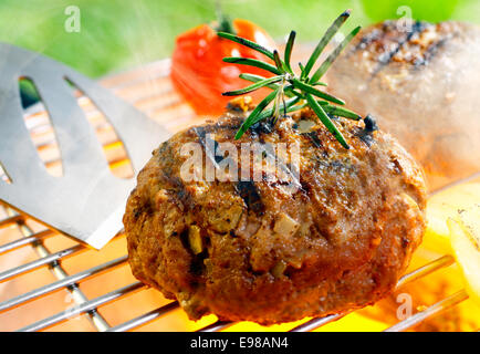 Hamburger patty grilling on the barbecue isolated on Stock Photo