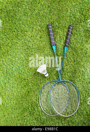 Overhead view of a pair of badminton racquets and a shuttlecock lying on a green lawn with copyspace Stock Photo