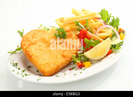 Delicious golden heart shape veal escalope covered in fried breadcrumbs and served with a healthy fresh mixed salad and crisp French fried potato chips Stock Photo