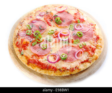 Whole cooked homemade pepperoni or salami pizza with cheese, spicy sausage, tomato, onion and chilli peppers served on a wooden Stock Photo