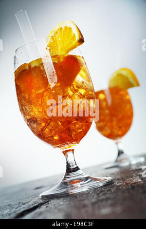 Golden orange and rum cocktail aperol sprizz served in long stemmed glasses on an old wooden counter top, low angle tilted view Stock Photo