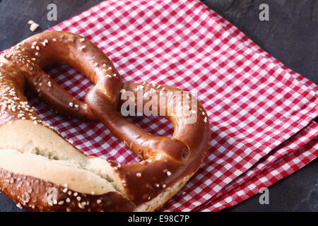 Close-up of a traditional homemade German pretzel, on a checkered red and white kitchen towel Stock Photo