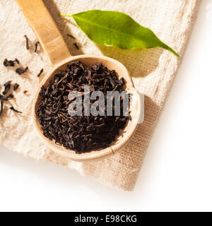 Close up overhead view of a small rustic wooden spoon filled with loose dried shredded tea leaves for making a refreshing brew or infusion to drink
