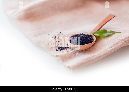 Shredded dried loose-leaf tea for brewing a delicious fresh cup of hot beverage displayed on a small wooden spoon on a folded napkin with copyspace Stock Photo