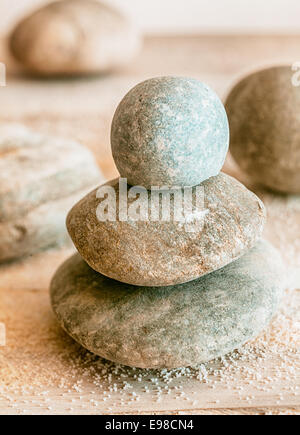 Stacked natural rounded weathered Zen stones with scattered beach sand conceptual of a spa, wellness, spirituality and meditation Stock Photo