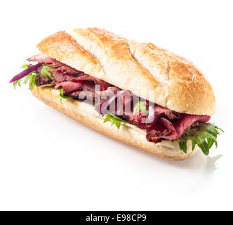 Healthy lean roast beef with leaves of fresh rocket on a freshly baked crusty roll or baguette viewed at an angle on a white background Stock Photo