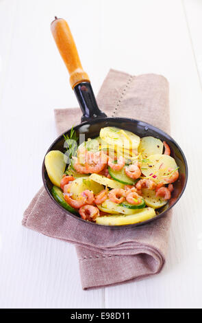 High angle view of tasty pan fried shrimps or prawns and potatoes served hot in a metal skillet Stock Photo