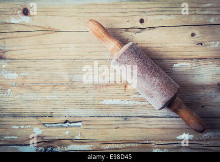 Old wooden rolling pin on a grunge wood background with remnants of scattered flour left over from baking overhead view with copyspace Stock Photo