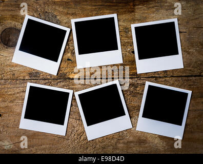 Overhead view of six retro blank instant photo frames with copyspace arranged on a rough textured wooden plank recalling memories of a bygone era or vacation Stock Photo