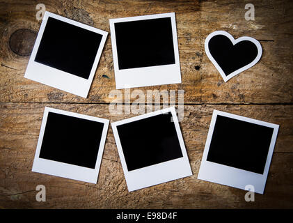 Six empty instant photo frames lying on rustic rough weathered wooden boards, with one heart-shaped for a nostalgic Valentine or anniversary keepsake or memento , overhead view Stock Photo