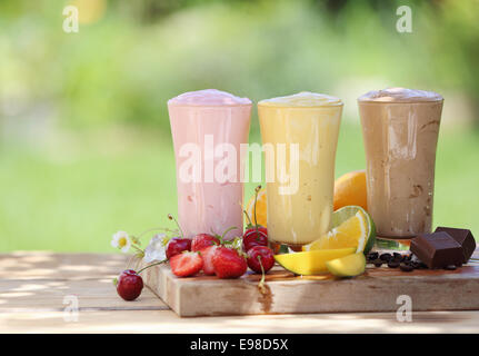 Three fruit or choclate smoothies or milkshakes with fresh organic ingredients including strawberries, cherries, citrus, coffee Stock Photo