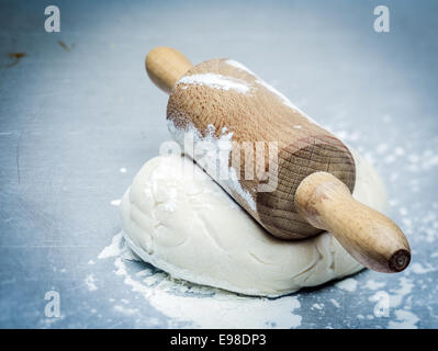 Mound of dough that has been allowed top rise topped with an old-fashioned wooden rolling pin ready to be flattened to make cookies or a pie crust Stock Photo