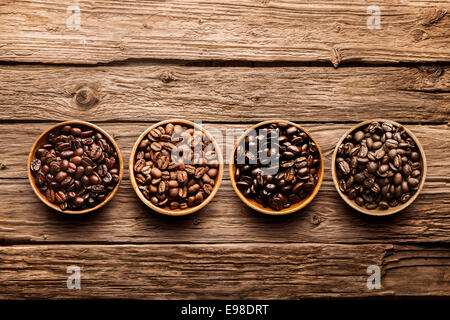 Assorted raw and roasted coffee beans in small individual containers on a rustic, weathered textured driftwood background, overhead view with copyspace Stock Photo