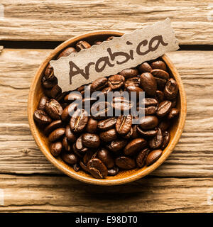 Close up of a bowl full of Arabica coffee beans over an old wooden table Stock Photo