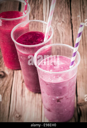 Healthy delicious trio of different berry smoothies with low fat yogurt arranged in a diagonal row, high angle view on an old rustic wooden background Stock Photo
