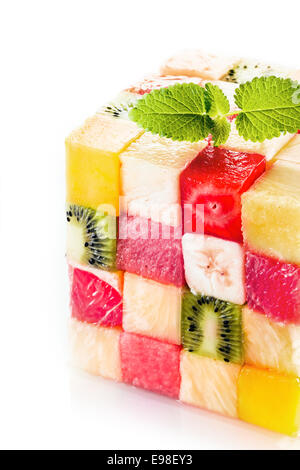 Decorative cube of colorful tropical fruit squares with kiwifruit, melon, watermelon, banana and strawberry garnished with a sprig of peppermint for a central buffet display Stock Photo