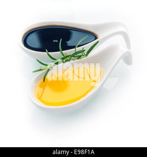 Sprig of fresh rosemary for seasoning food with golden virgin olive oil in a ceramic spoon on a white background for healthy cooking and cuisine Stock Photo