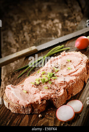 Savory smoked teewurst , a German sausage made of bacon and pork, on rye bread with black pepper, radishes and chopped chives Stock Photo