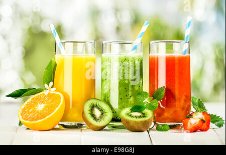 Delicious array of fresh fruit juices served in tall glasses made from liquidised orange, kiwifruit with peppermint, and strawberries for healthy summer treats rich in vitamins Stock Photo