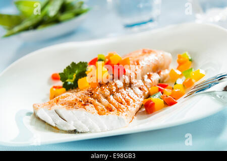 Delicious healthy grilled fish fillet served on a platter with a colorful fresh salad for a tasty seafood dinner Stock Photo