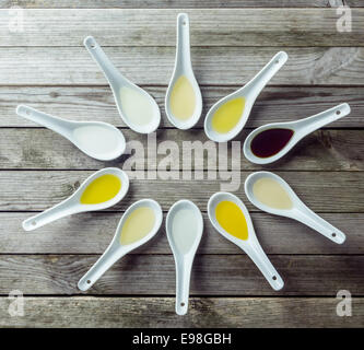 Several Chinese soup spoon filled with different colored liquid on wooden surface Stock Photo