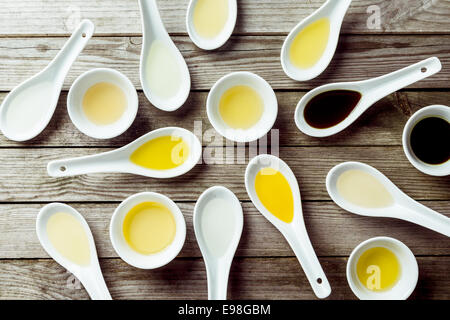 Several soup spoons and sauce dishes arranged randomly on wooden surface Stock Photo