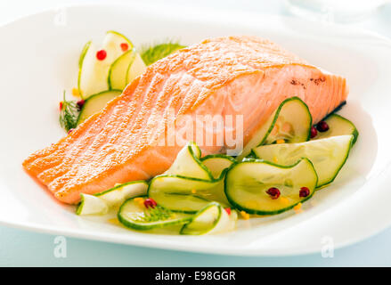 Gourmet oven-baked pink salmon steak served with thinly sliced cucumber as a delicious seafood starter to a dinner Stock Photo