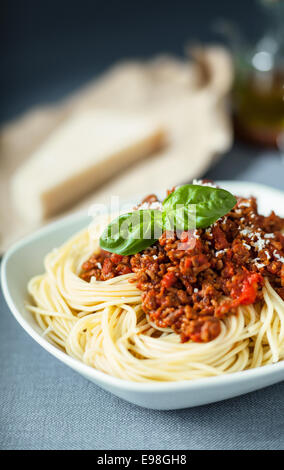 Traditional Italian spaghetti Bolognese topped with grated with parmesan cheese sprinkled on a tomato based meat sauce garnished with basil leaves Stock Photo