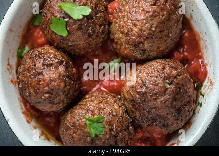 Serving of delicious seasoned meatballs in tomato sauce garnished with fresh herbs, overhead view in a saucepan Stock Photo
